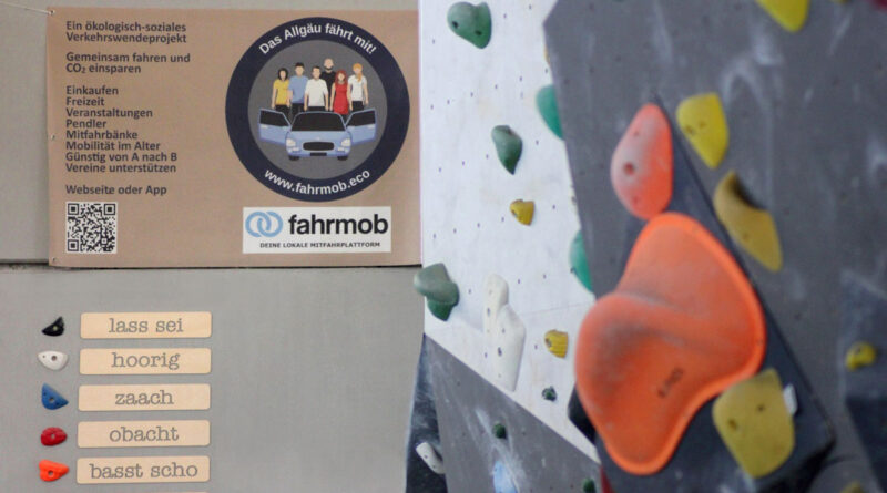 Eine Boulderwand in der Nahaufnahme, im Hintergrund ein Banner des Sponsors