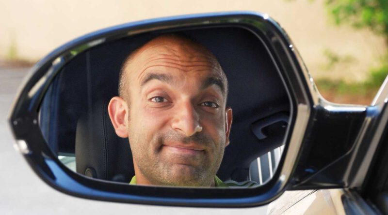 Das Gesicht des Künstlers Django Asül im Rückspiegel eines Fahrzeugs