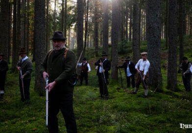 Szene aus dem Film mit Männern die mit Gewehren durch einen Wald ziehen