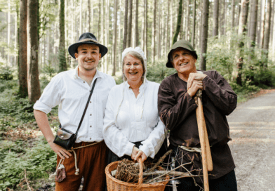 Drei historisch gekleidete Personen auf einem Waldweg