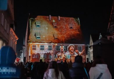 Vor dunklem Nachthimmel wird das Gebäude der ehemaligen Kramerzunft in Memmingen mit einem Video angestrahlt, das in imposanten Bildern die Ereignisse um 1525 erklärt. Davor steht eine große Menschenmenge