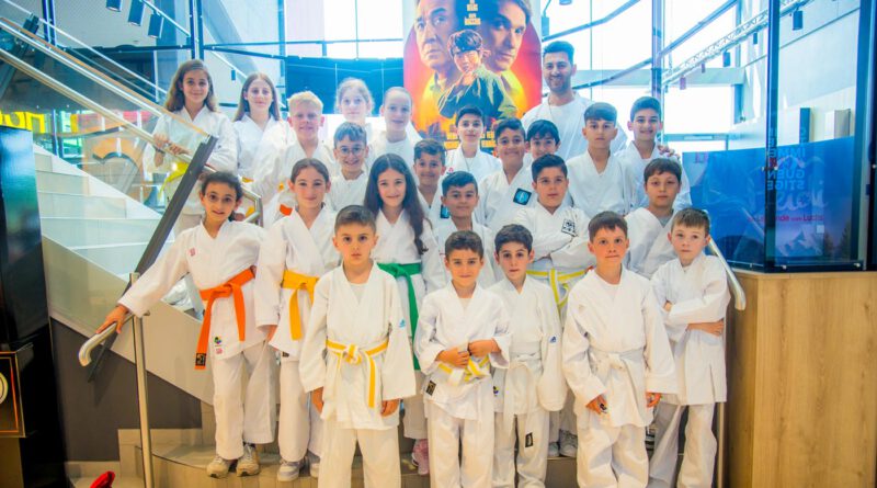 Die Kinder des SV Steinheim stehen in Karate-Anzügen auf einer Treppe im Kinofoyer, im Hintergrund das Filmplakat zu einem Karate-Film