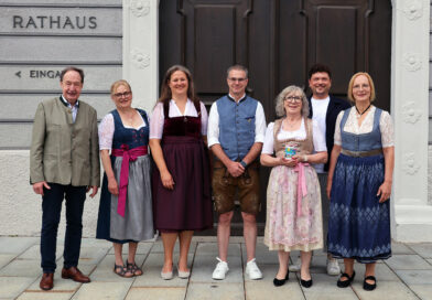 Mehrerer Personen, teilweise in Tracht gekleidet, stehen für ein Gruppenbild vor dem Tor des Rathauses