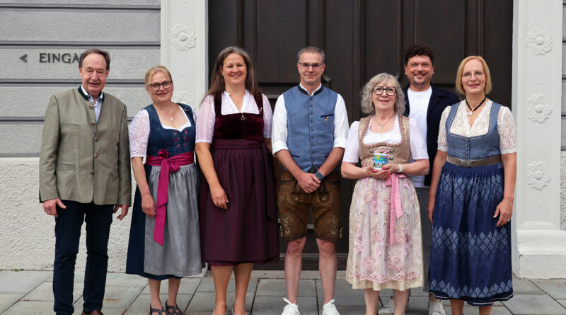 Mehrerer Personen, teilweise in Tracht gekleidet, stehen für ein Gruppenbild vor dem Tor des Rathauses