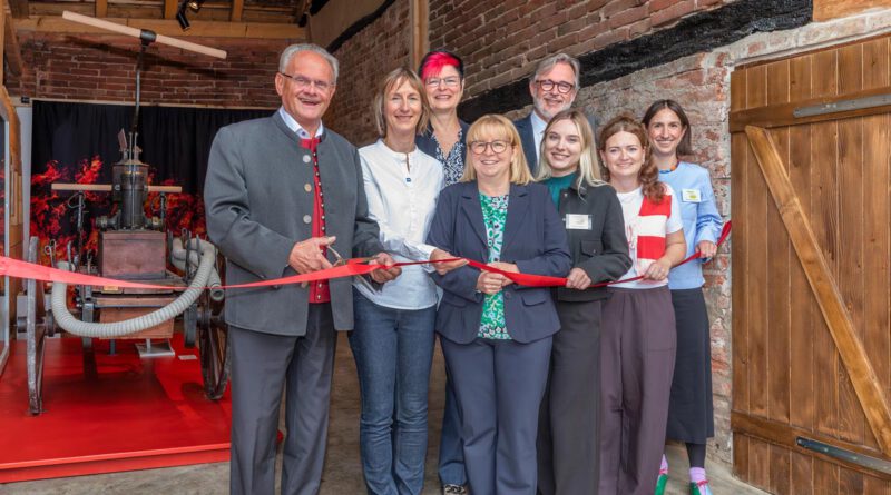 Menschen zerschneiden feierlich ein rotes Band vor einer Ausstellung in einem historischen Gebäude