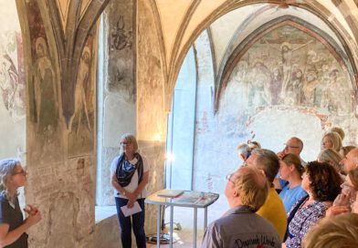 menschen besichtigen gotische Gewölbe mit Malereien