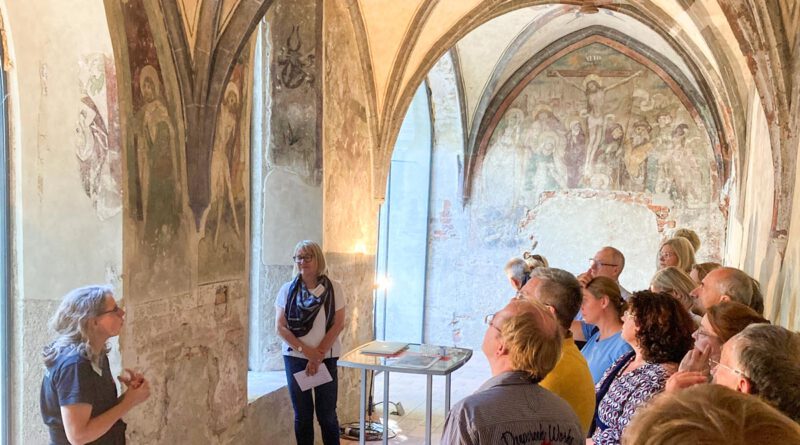 menschen besichtigen gotische Gewölbe mit Malereien