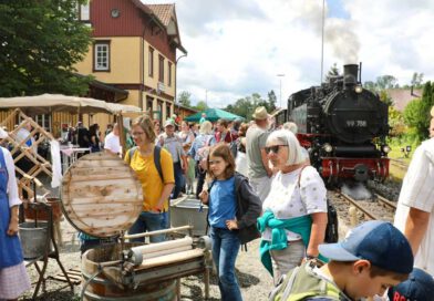 Menschen auf dem Bahnsteig vor einer historischen Dampflok