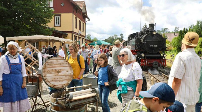 Menschen auf dem Bahnsteig vor einer historischen Dampflok