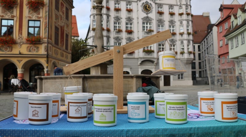 Behälter mit Fakten zur CO2-Einsparung stehen auf einem Tisch vor dem Memminger Rathaus