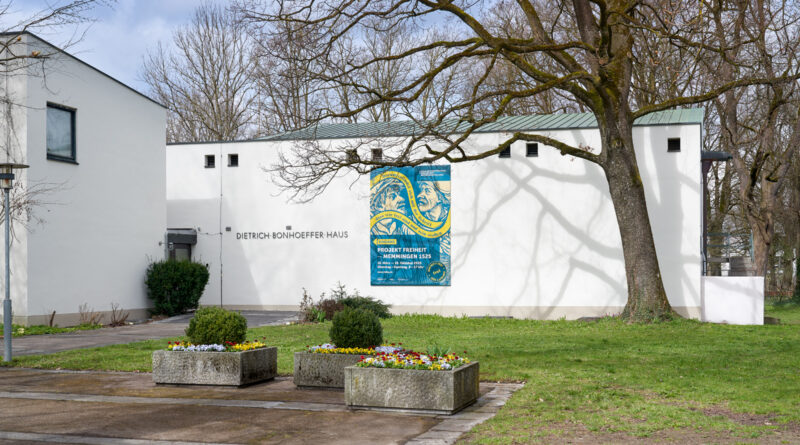 Ein weißes Gebäude im Park mit einem großen Ausstellungsbanner an der Außenwand