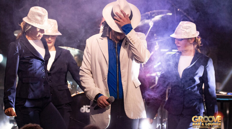 <span style="font-size: 16px;">20. März, Memmingen </span><br>„Michael Jackson Tribute live Experience“ Ein Michael Jackson-Double in weißem Anzug umringt von Tänzerinnen auf einer blau ausgeleuchteten Bühne