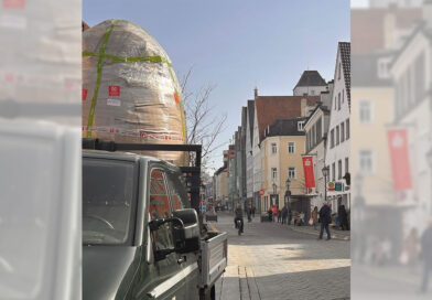 auf einem Transporter, der über den Weinmarkt fährt, steht eine große, verpackte, eiförmige Skulptur