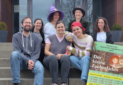 Mitglieder des Theatervereins sitzen zum Teil mit lustigen Hüten auf einer Treppe