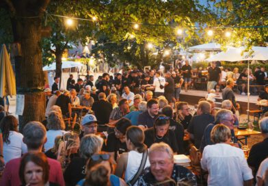 feiernde Menschen in einem gemütlich beleuchtetem Biergarten in der Dämmerung